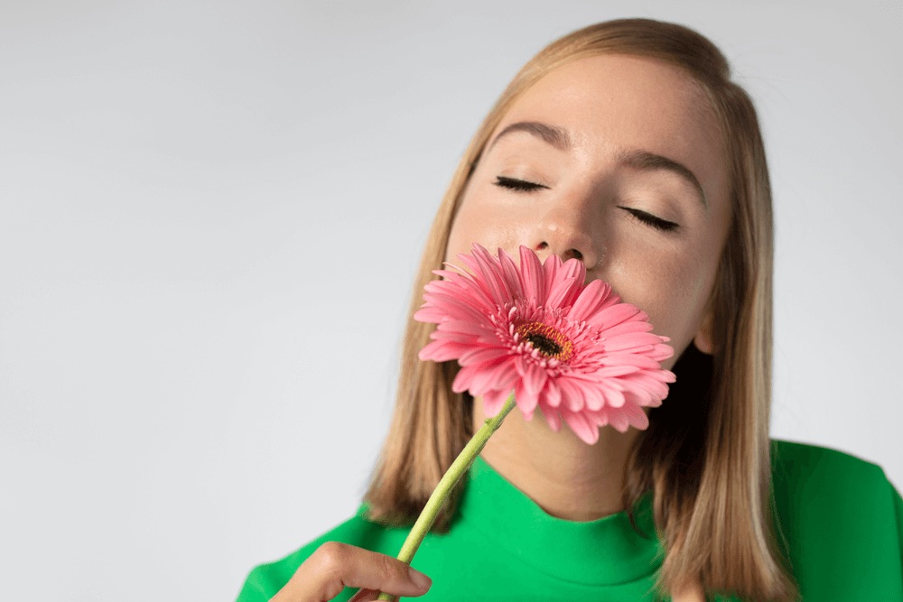 Frau mit geschlossenen Augen hält eine Blume